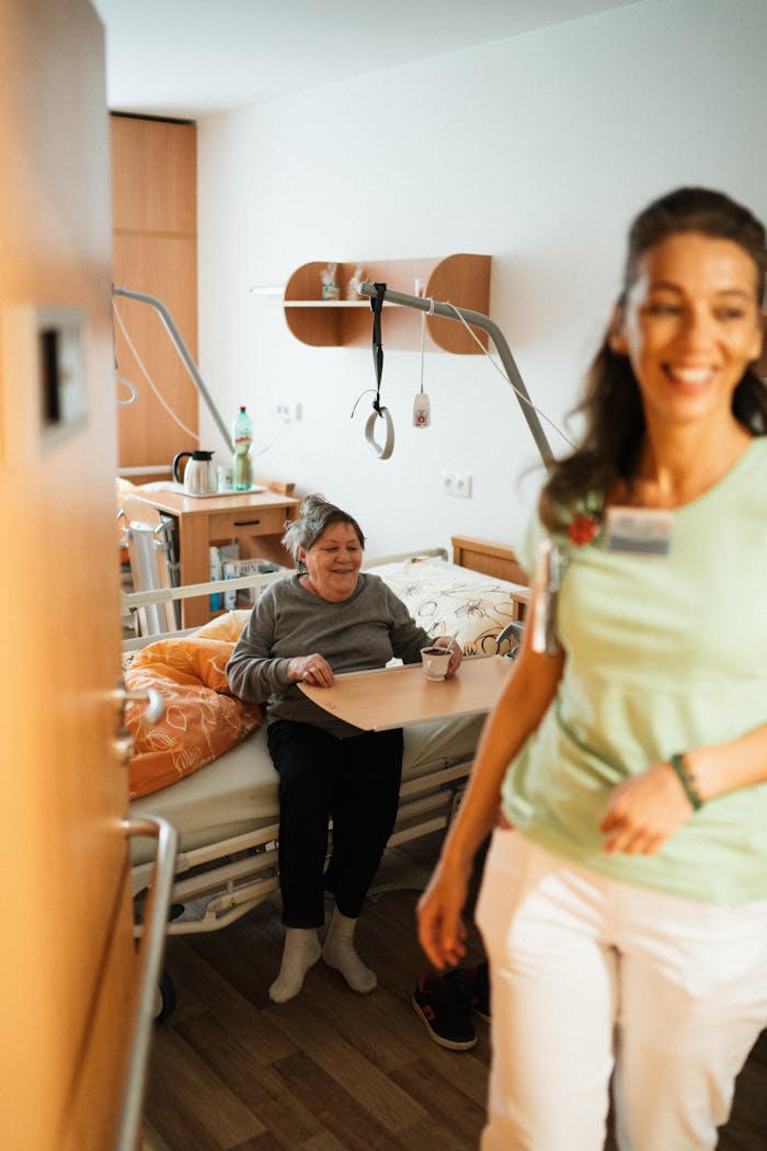 Smiling nurse assists senior patient in a cozy hospital room, promoting healthcare and wellbeing.